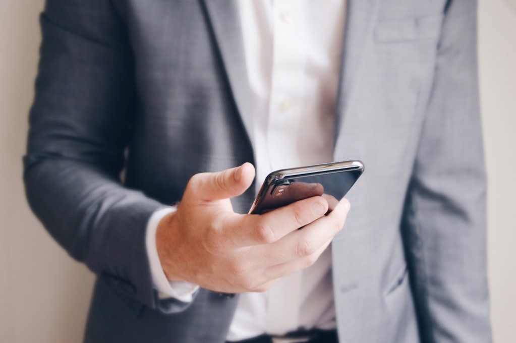 midsection-of-a-businessman-holding-his-mobile-phone-texting-or-preparing-a-call-bright-and-modern_t20_wQ90W0