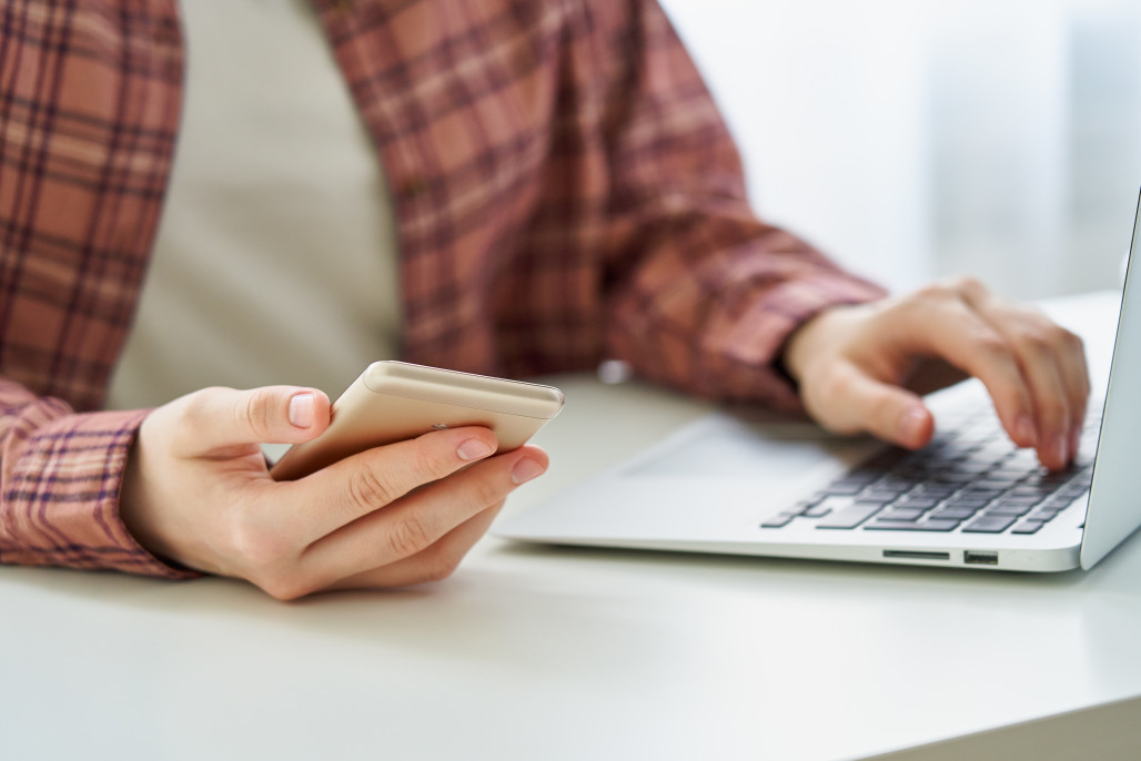 unrecognizable-woman-surfing-mobile-phone-while-entering-data-on-computer-cybersecurity-awareness-and_t20_Nlxr3B